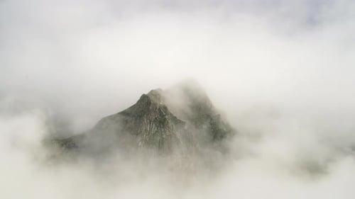 Mountain Peak Emerging Through Swirling Clouds, Aerial View
