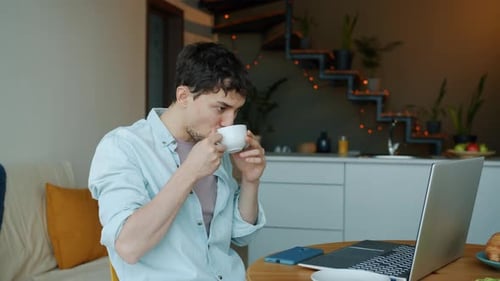 Man Drinks Coffee While Working at Home
