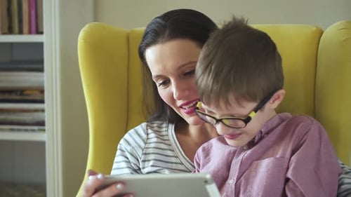 Mother and Son Using Tablet Together in Yellow Chair