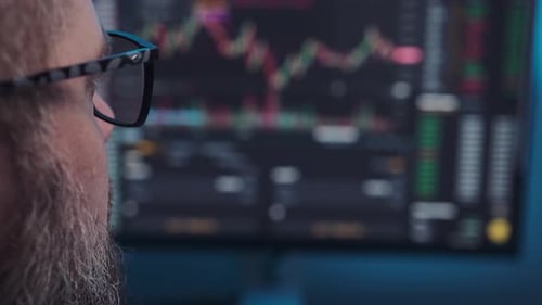 Mature Stock Market Trader or Broker Analyzing Data and Graphs on Multiple Computer Screens While