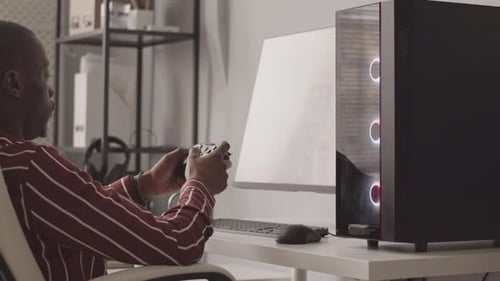 Young Adult Playing Video Game on Modern Computer