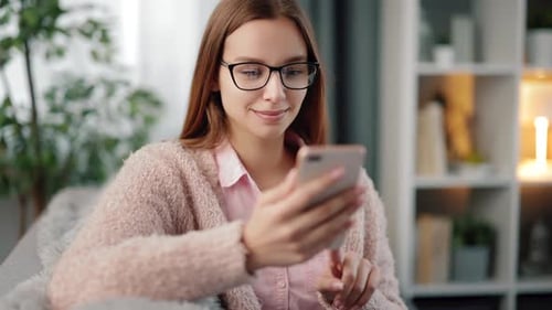 Woman Smiling Using Cellphone on Sofa Indoors
