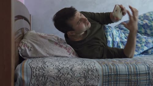 Man Wakes Up and Uses Smartphone in Bed