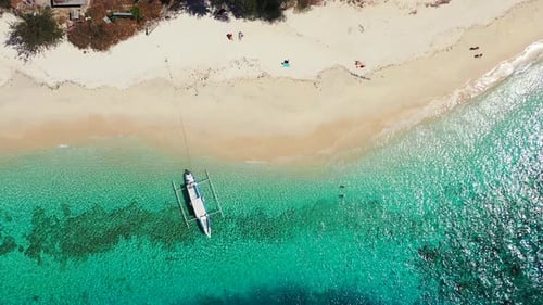 Antigua, white sand beach, turquoise water and small boat floating in the clear sea. Aerial