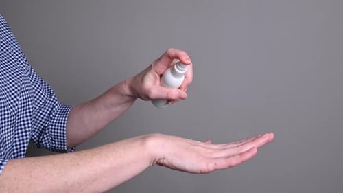 Hands Spraying Bottle of Sanitizer