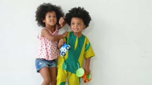 Two African American child enjoy to play with jumping in the living room with white wall