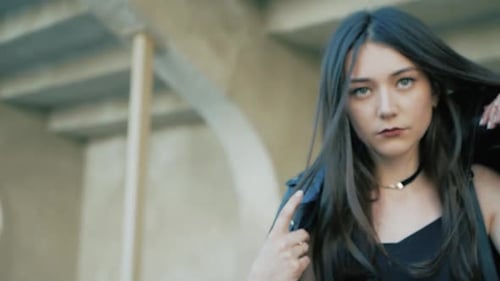 Woman Puts on Leather Jacket in Urban Setting