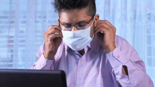 Man Wearing Mask Works on Computer at Home