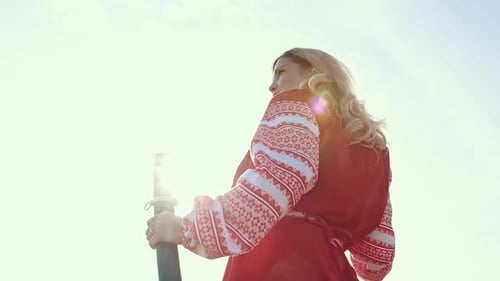 Woman in Dress Holds Sword to the Sky