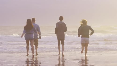 Group of friends at beach running in surf