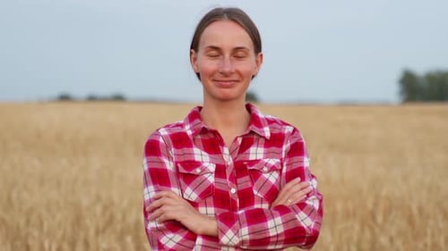 Portrait of a Pretty Farmer Woman with Her Arms Crossed Standing in a Wheat Field and Looking at the