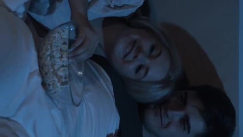 Young Couple Laughing, Eating Popcorn in Bed