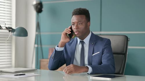 African Businessman Talking on Smartphone in Office