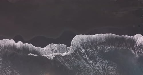 Aerial View. Stunning Aerial Footage of Waves Breaking Against Beautiful Icelandic Black Sand Beach.
