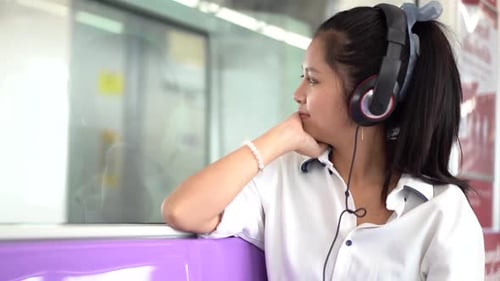 Woman Listening to Headphones While Traveling by Train