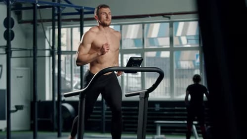 Athletic Man Runs on Treadmill at Gym