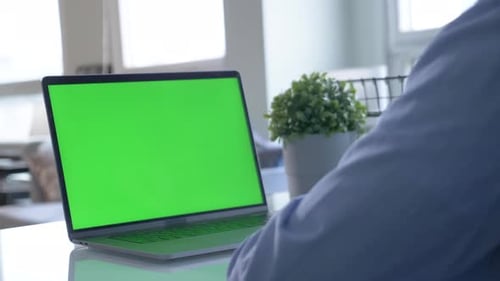 Close-up of male hands using green screen chroma key laptop typing working in light office