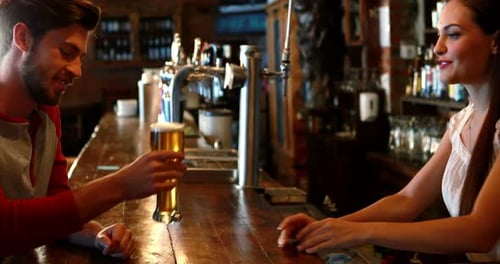 Bartender Serving Beer to Man at Wooden Bar