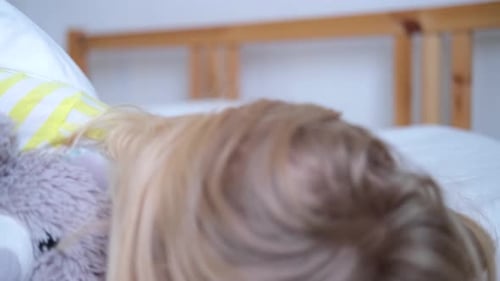 Joyful Girl Laughing in Bed with Stuffed Animal