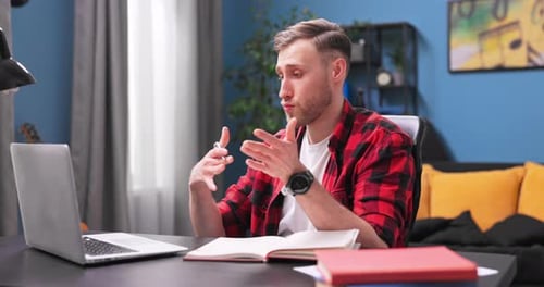 A Focused College Student Boy is Video Chatting on a Laptop