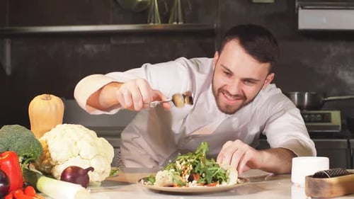 Young Adult Male Chef Garnishing a Salad