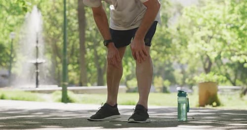 Senior man in pain holding his leg in the park