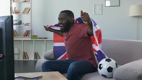 Enthusiastic Man Cheers Watching Soccer with British Flag