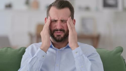Man Rubs Temples Suffering a Headache Indoors