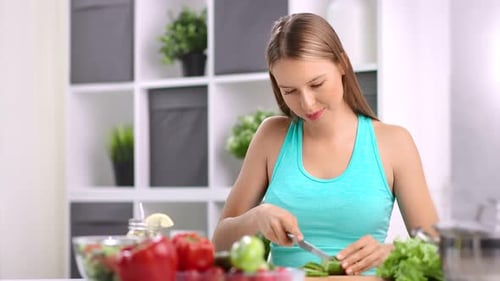 Young Woman Slices Cucumber in Bright Kitchen