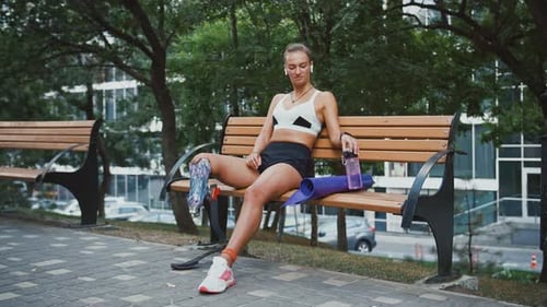 Athletic Woman Relaxing With Prosthetic Leg on Bench