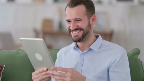 Excited Man Using Tablet at Home