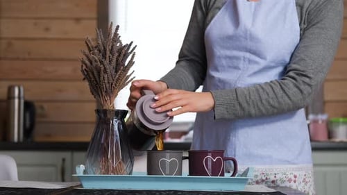 Woman Pours Coffee in Cozy Kitchen Setting