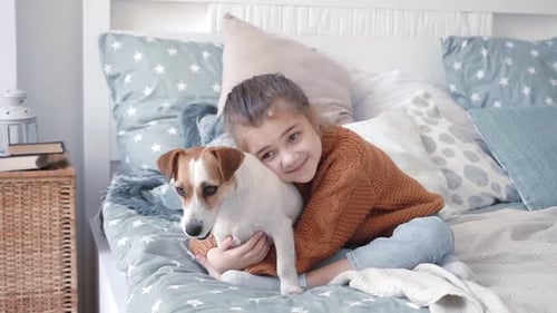 Girl Cuddling her Jack Russell Terrier on Bed