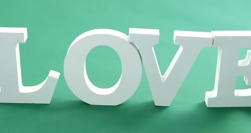 Gift box and alphabet love on green background