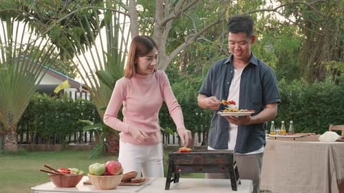 Happy Asian family having a barbecue-BBQ party together in the garden at home.