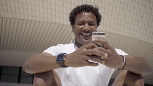 Smiling Man Using Smartphone Outdoors on Sunny Day