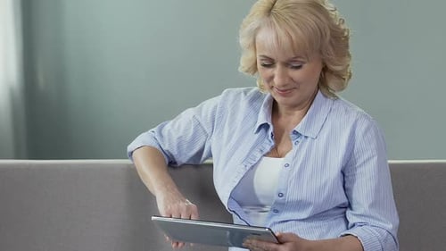 Mature Woman Using Tablet on Couch Indoors