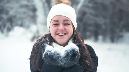 Woman Blowing Snow from Gloved Hands in Winter