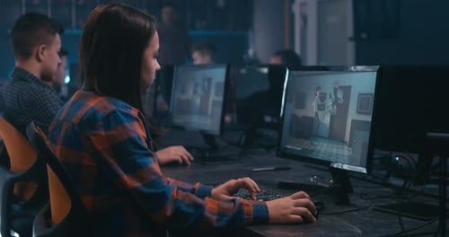Young Adults Coding at Computers in Dark Office