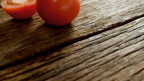 Tomates enteros y medio dispuestos sobre suelo de madera 4K 4k