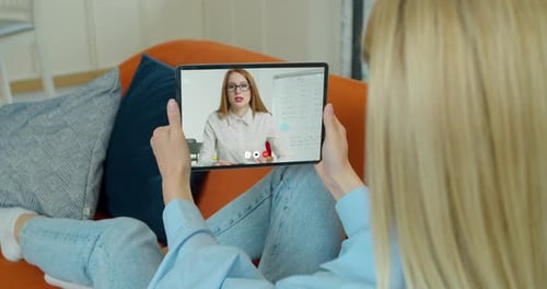 Woman Using Tablet For Video Conference on Sofa