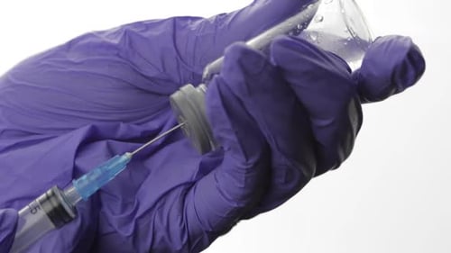 Medical Professional Draws Fluid from Glass Vial