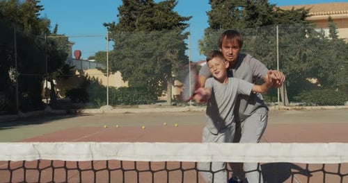 Father Teaching Son to Play Tennis
