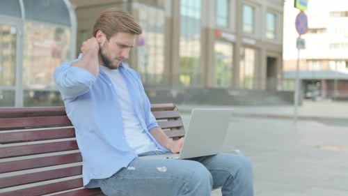 Young Adult Using Laptop on Bench Outdoors