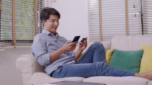 Man Relaxing at Home Using Smartphone and Credit Card