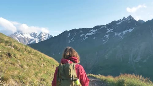Lady Walks on Hill Slope Path Covered with Thick Grass