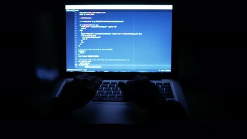 Hands Typing Code on a Laptop at Night