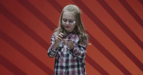 Girl Eating Sandwich Cookie Against Red Background