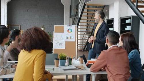 Mature Man Making Presentation for Business Team Discussing Achievements Clapping Hands in Office