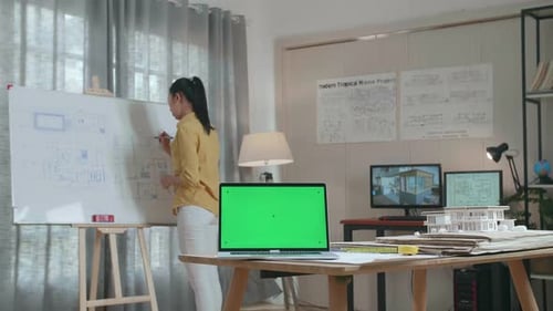 Asian Woman Engineer With Green Screen Laptop Drawing Blueprint On The Whiteboard At The Office